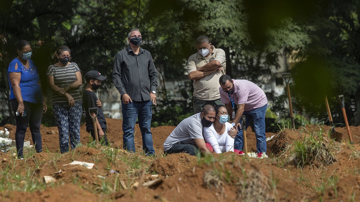 Brezilya'nın  Sao Paulo kentinde Covid-19 nedeniyle yaşamını yitiren bir kişinin yakınları, mezarı başında göz yaşı döktü