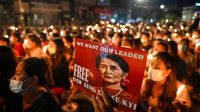 A protester holds a poster with an image of detained civilian leader Aung San Suu Kyi during a candlelight vigil to honour those who have died during demonstrations.