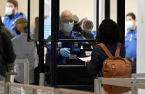 A TSA agent assists a traveller at a security checkpoint at Love Field Airport, Dallas, 24 Nov 2020