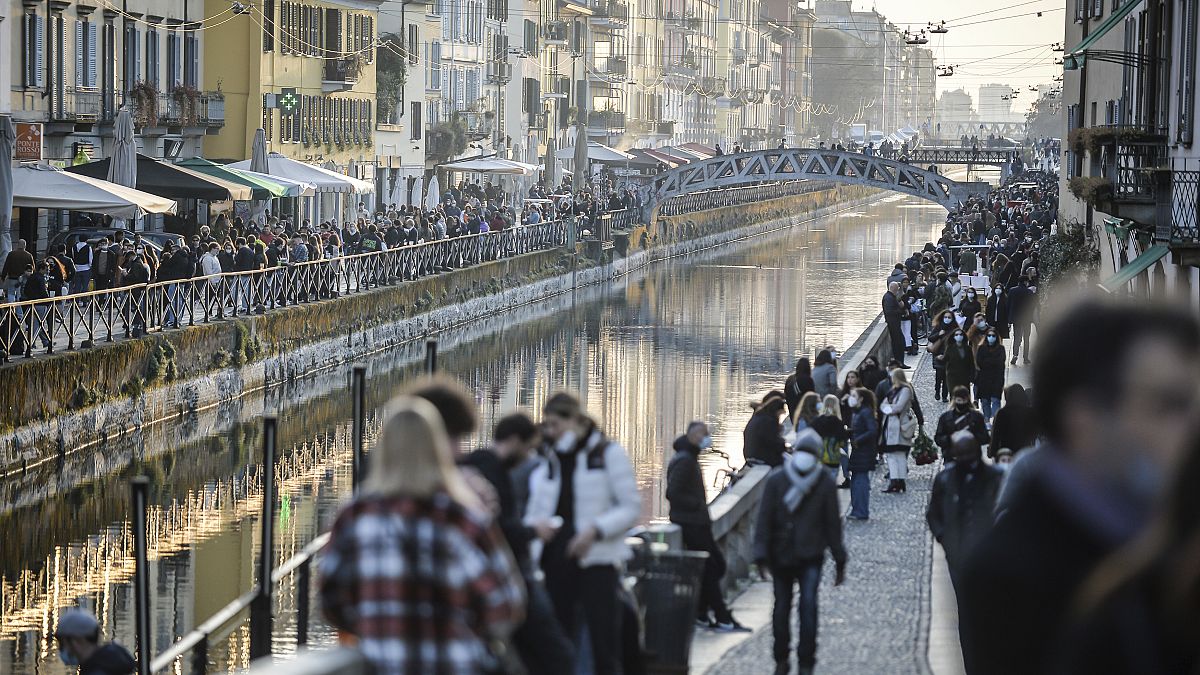 People stroll in the Navigli popular area Milan, Italy, Saturday, March 13, 2021.