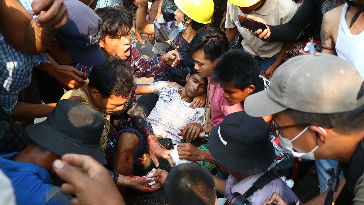 Des manifestants opposés au coup d'État entourent un homme blessé à Rangoun le 14 mars 2021.