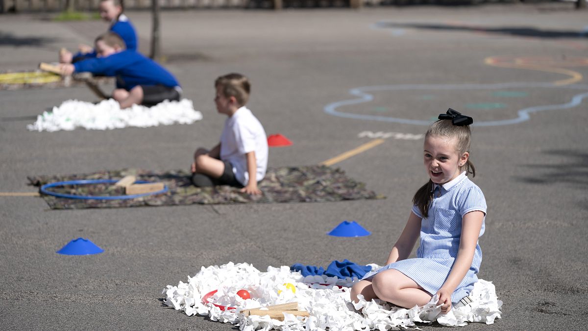 Children at Seymour Road Academy sit in designated areas in the playground during the coronavirus outbreak in Manchester, England, Wednesday May 20, 2020.