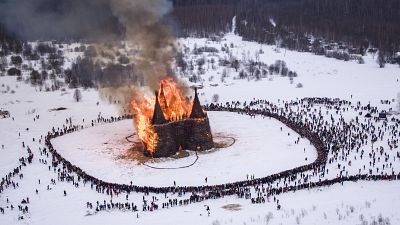 People watch a castle-shape wooden construction burning as part of celebrations at the Maslenitsa (Shrovetide) festival at the Nikola-Lenivets art park