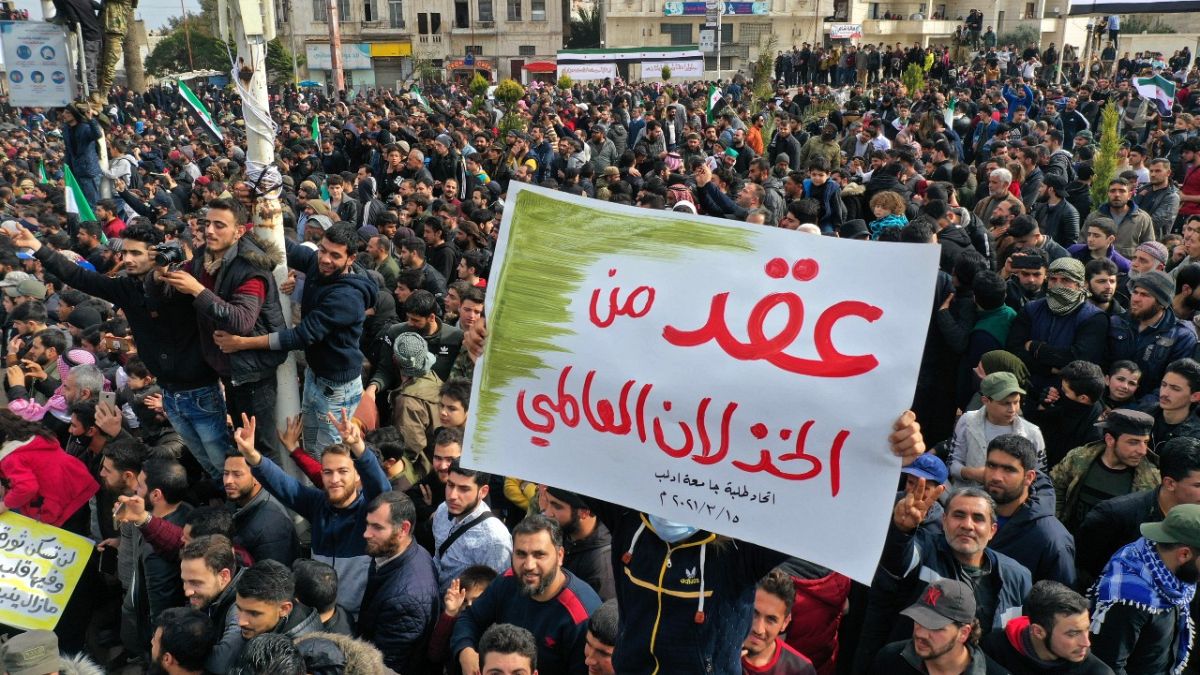 تظاهرة بذكرى اندلاع "الثورة السورية" في إدلب ولافتة مكتوب عليها عقد من الخذلان العالمي