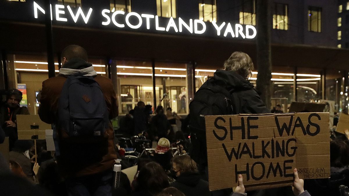 People hold signs outside New Scotland Yard during a march to reflect on the murder of Sarah Everard, in London, March 15, 2021. 