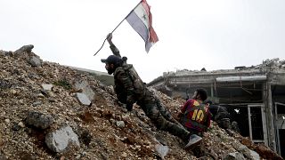 In this Dec. 5, 2016 file photo, a Syrian army soldier places a Syrian national flag during a battle with rebel fighters at the Ramouseh front line, east of Aleppo, Syria.