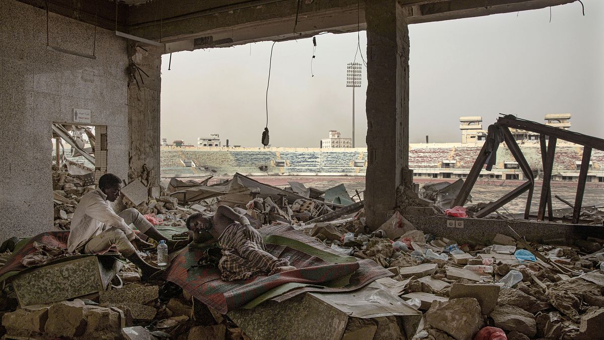 مهاجرون إثيوبيون في "ملعب 22 مايو لكرة القدم" الذي دمرته الحرب في عدن، اليمن.