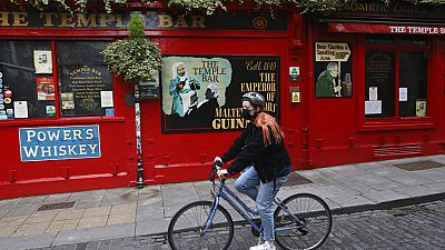 A cyclist passes a closed bar in the Temple bar area of Dublin, Ireland, Wednesday, Oct. 21, 2020