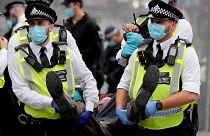 olice officers with face masks carry a protestor away during an Extinction Rebellion climate change protest at Parliament Square in London.