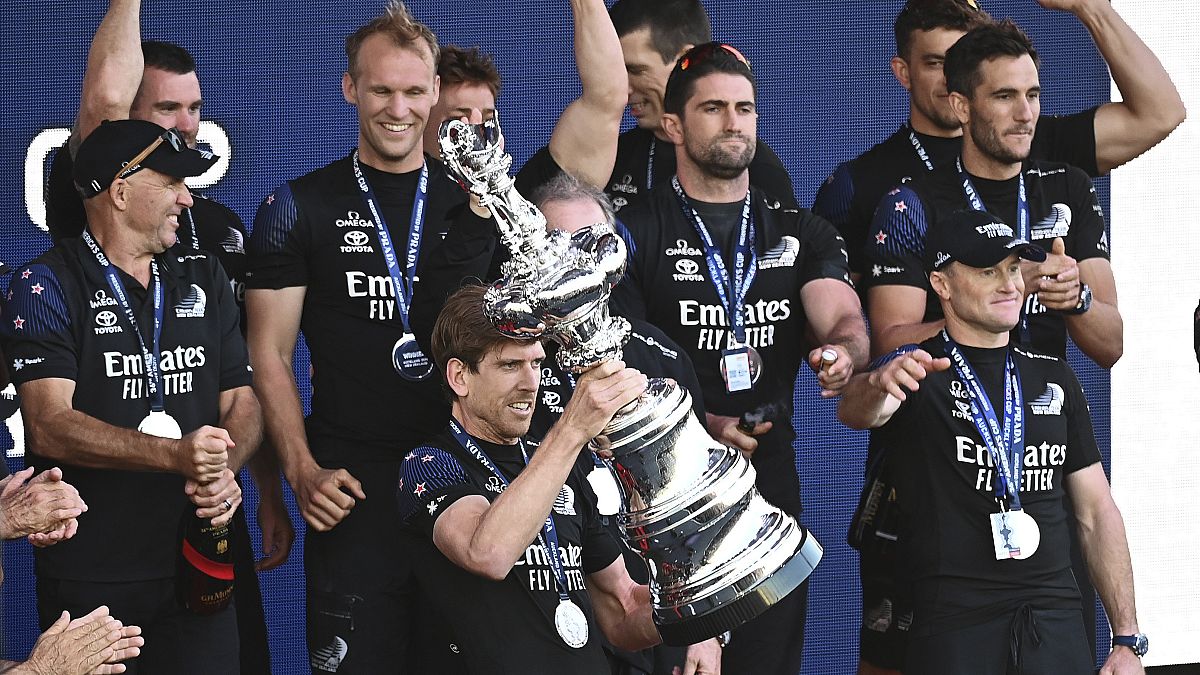 Le barreur de Team New Zealand, Peter Burling, brandissant l'Aiguière d'argent, le trophée de la Coupe de l'America, le 17 mars à Auckland.