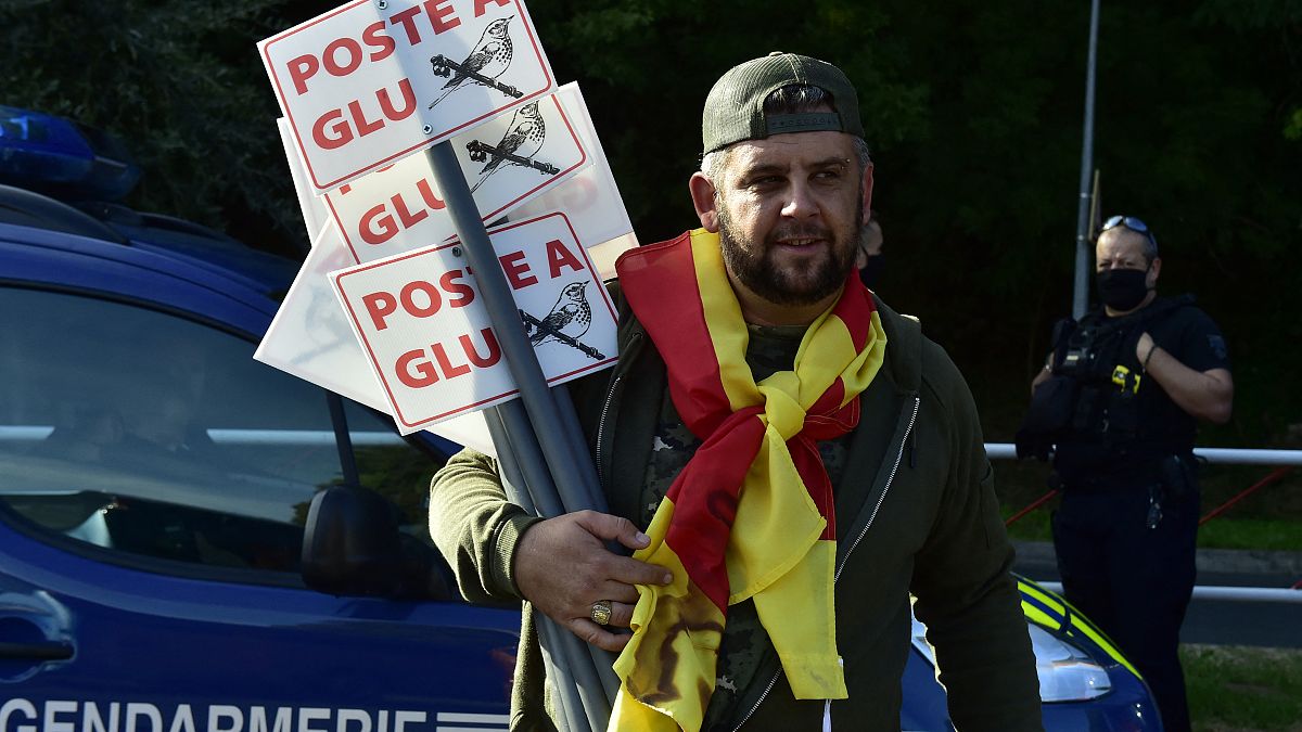 A protester holds a sign as he takes part in a demonstration of hunters to denounce the ban on glue hunting, in Prades, southwestern France, on Septembre 12, 2020