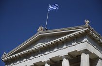 A worker adjusts the Greek flag atop of the old National Library building in Athens.