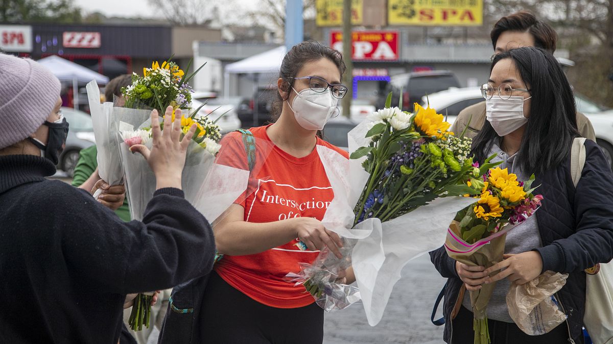 Roula AbiSamra, center, and Chelsey (last name withheld), right, prepare to lay flowers bouquets at a makeshift memorial outside of the Gold Spa in Atlanta, Wednesday.