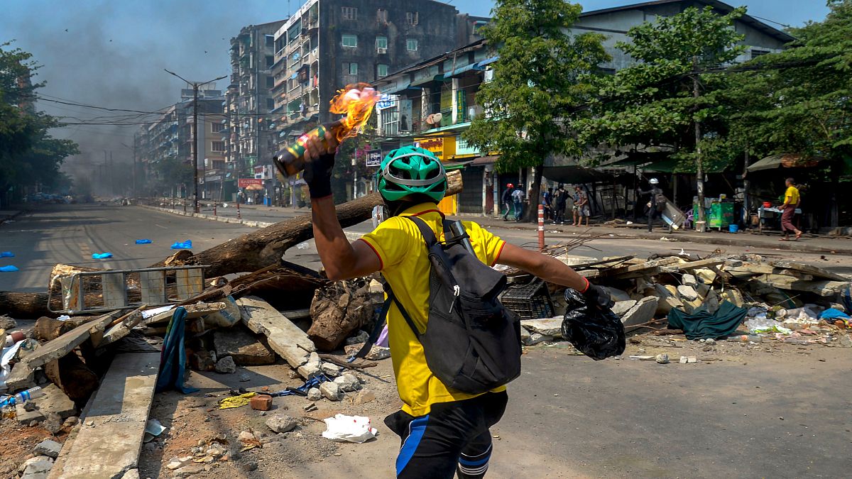 An anti-coup protester throws a molotov cocktail towards police as they move towards the protest area in Yangon