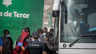 Migrants board a bus to be transferred after being rescued by the Spanish coast guard in the Canary Islands