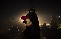 Una donna sfollata da uno degli ultimi territori in mano allo Stato islamico, nel deserto alle porte di Baghouz, in Siria, mentre viene controllata dalle forze siriane