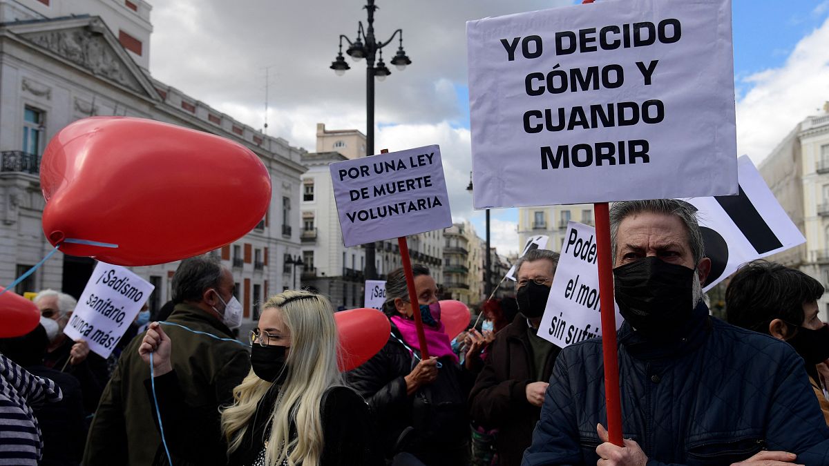 A man holds a placard reading "I decide when and how to die" during a demonstration in support of a law legalising euthanasia in Madrid on March 18, 202