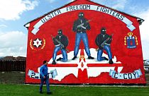 Ein Mann vor einem Mural-Wandbild der Untergrundbewegung Ulster Defence Association (Unionisten)