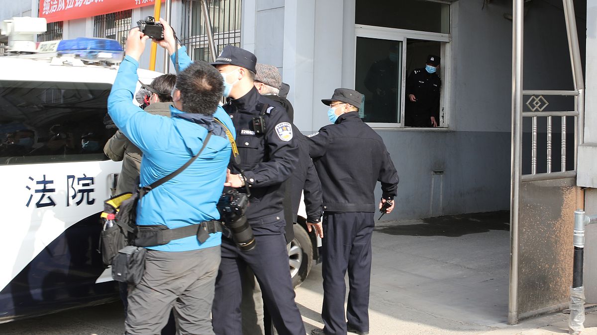 Security officers stand guard as a police van arrives at a court building in Dandong in northeastern China's Liaoning Province, Friday, March 19, 2021. 