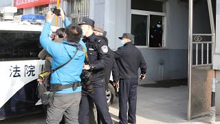 Security officers stand guard as a police van arrives at a court building in Dandong in northeastern China's Liaoning Province, Friday, March 19, 2021. 