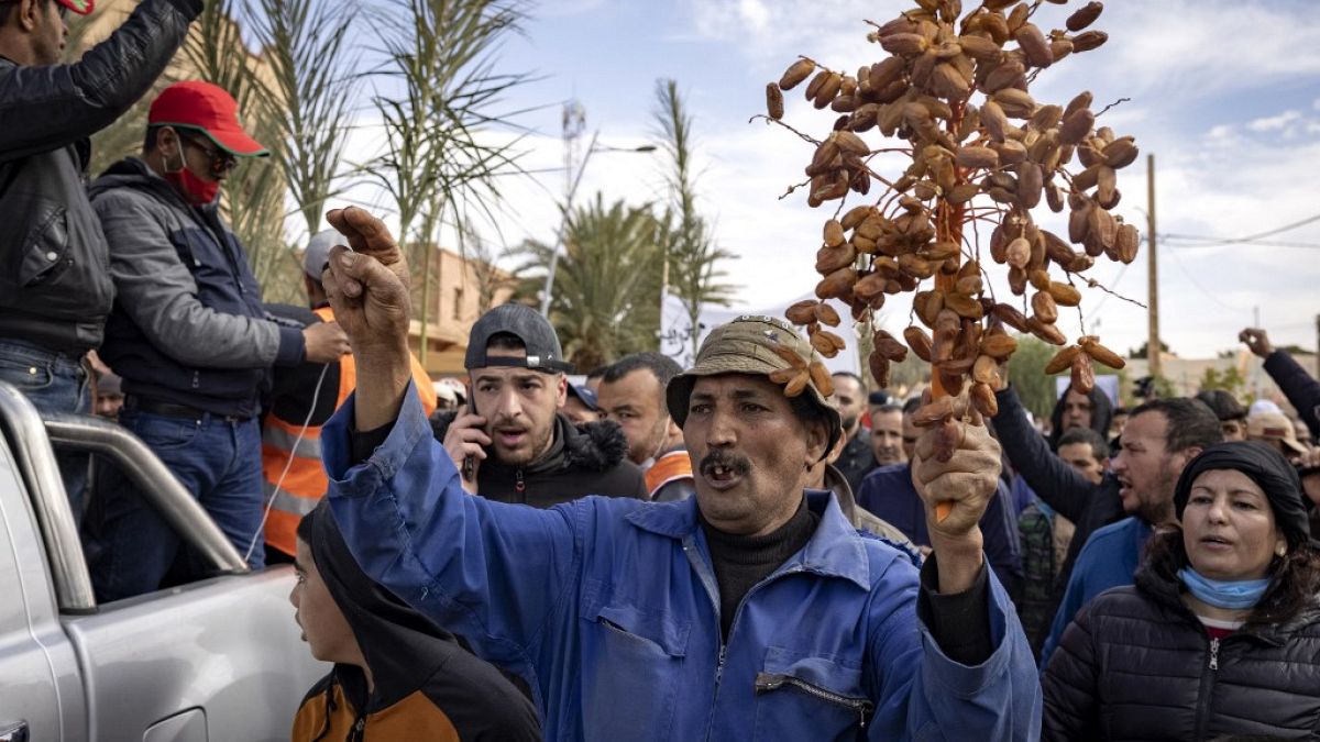 Un agriculteur portant une branche de dattes lors de la manifestation de Figuig, Maroc, 18 mars 2021