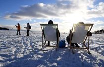 أشخاص يستمتعون بأشعة الشمس في الواجهة البحرية الجليدية في هلسنكي، فنلندا.