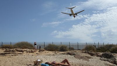 Eine Urlauberin sonnt sich an der Playa del Palma  auf Mallorca. Der nahegelegene Flughafen Son Sant Joan ist dort ziemlich allgegenwärtig