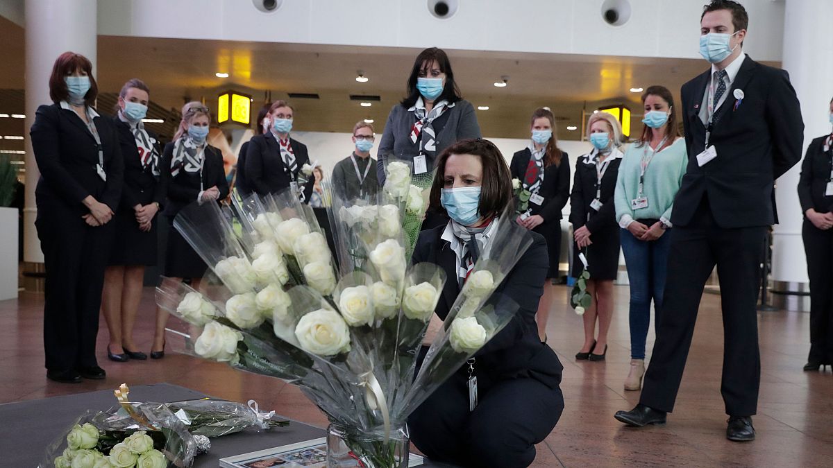 Representatives of victims and others carry flowers and photos at Brussels Airport