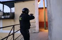 Agente da polícia com arma apontada entra num corredor de uma favela em Los Teques