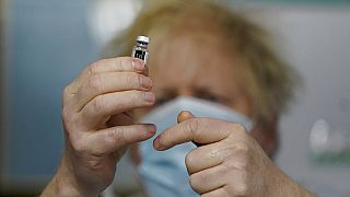 Britain's Prime Minister Boris Johnson holds a bottle of the Pfizer BioNTech vaccine