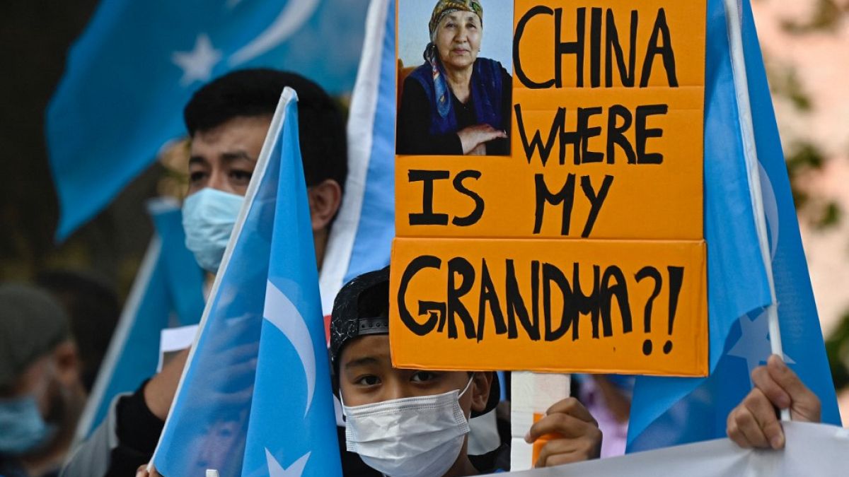 Uyghur activist holds up a poster that reads "China where is my grandma?!" 