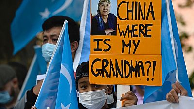 Uyghur activist holds up a poster that reads "China where is my grandma?!" 