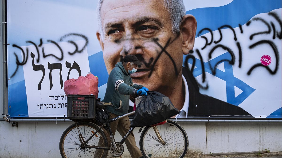 Mann vor einem Wahlplakat mit der Abbildung Netanjahus
