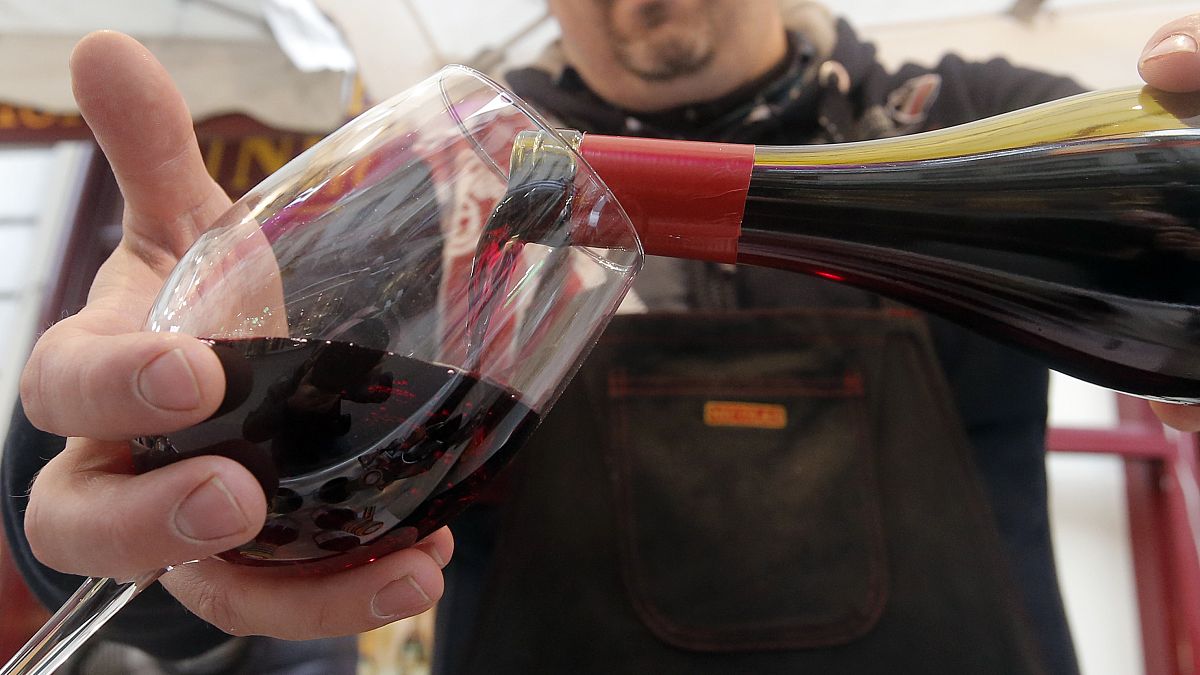 A wine storekeeper pours red wine in a glass during a presentation in a wine shop in Paris, Thursday Nov. 20, 2014