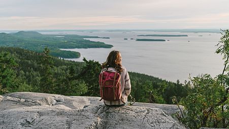 Scenic view of woman looking at lake in Finland at sunset.