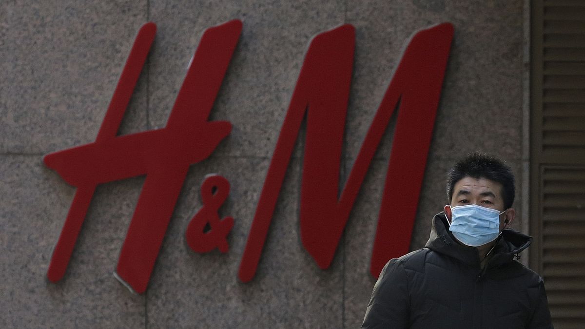 A man wearing a face mask walks by a Swedish fashion brand H&M store outlet in Beijing, March 25, 2021. 