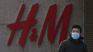 A man wearing a face mask walks by a Swedish fashion brand H&M store outlet in Beijing, March 25, 2021.