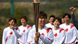Japanese torchbearer Azusa Iwashimizu, centre, during the torch relay grand start outside J-Village National Training Center in Naraha, northeastern Japan on March 25, 2021.