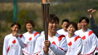 Japanese torchbearer Azusa Iwashimizu, centre, during the torch relay grand start outside J-Village National Training Center in Naraha, northeastern Japan on March 25, 2021.