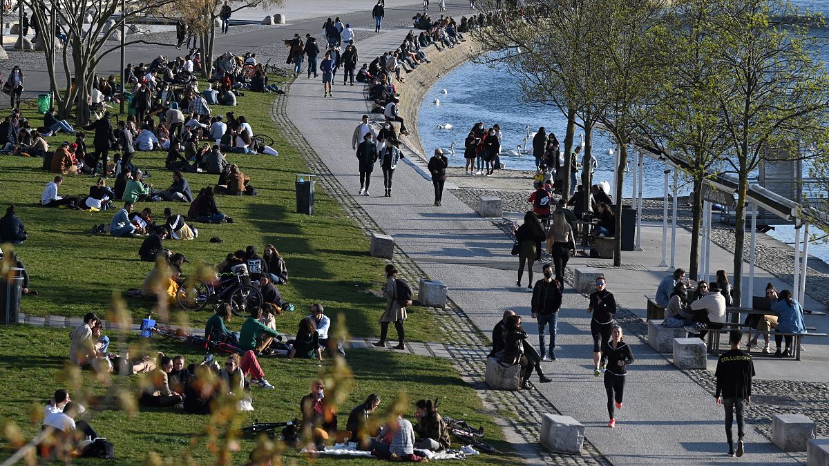 People take a break on a bank of the Rhône river in Lyon, south-eastern France, one of the new areas to have restrictions tightened,  on March 25, 2021. .