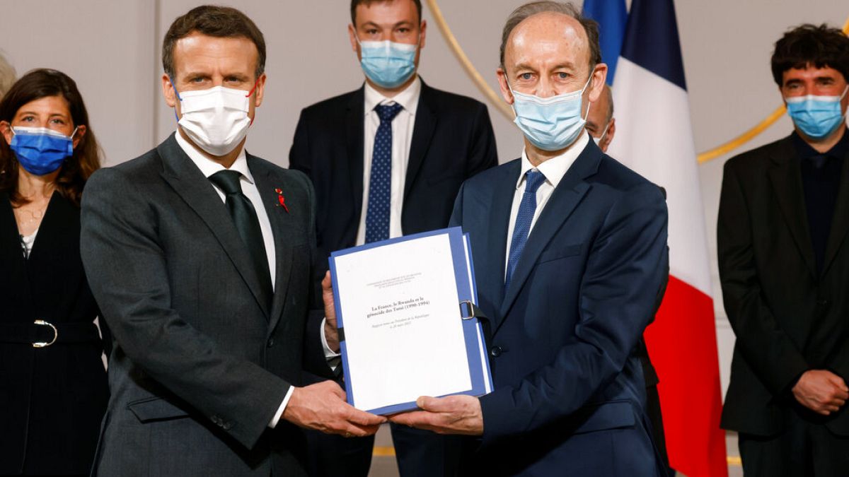 Historian Vincent Duclert, right, gives a report to French President Emmanuel Macron, at the Elysee Palace, in Paris, Friday, March 26, 2021.