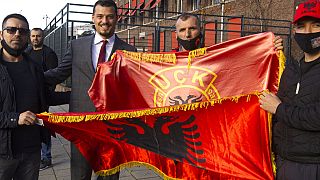 Endrit Thaci, third left, son of Hashim Thaci, poses outside the court building where Thaci is to face charges including murder, torture and persecution.