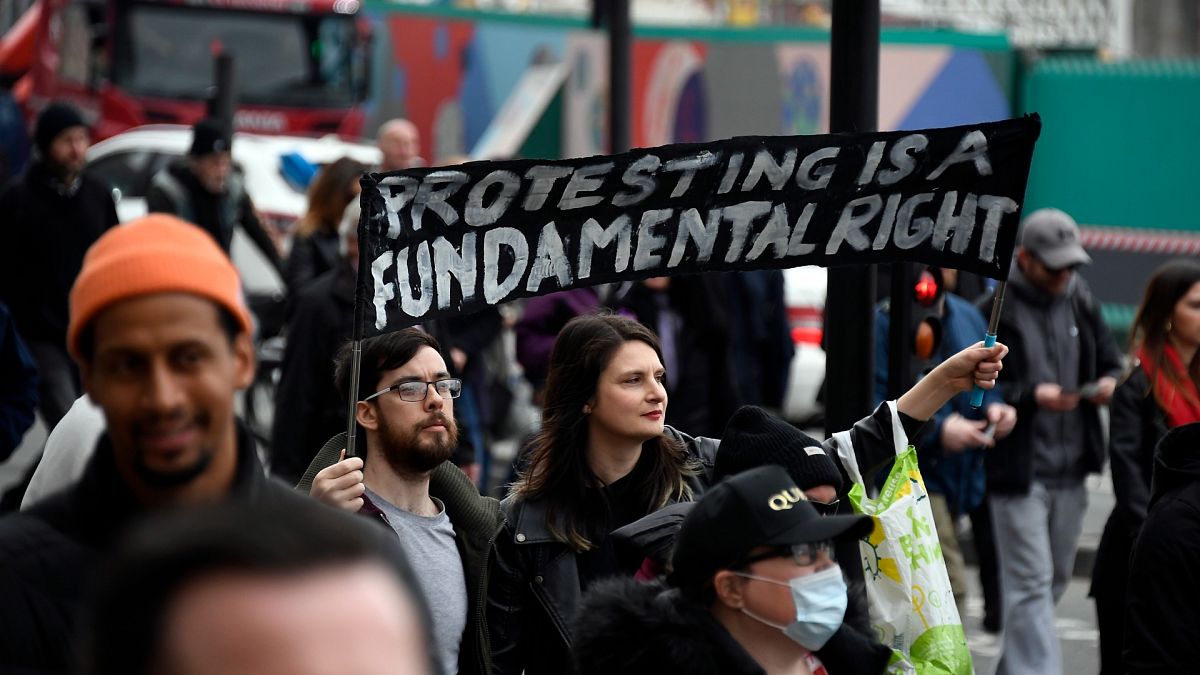 People hold signs during a protest against government restrictions to curb the spread of the coronavirus, in London, Saturday, March 20, 2021.