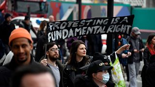 People hold signs during a protest against government restrictions to curb the spread of the coronavirus, in London, Saturday, March 20, 2021.