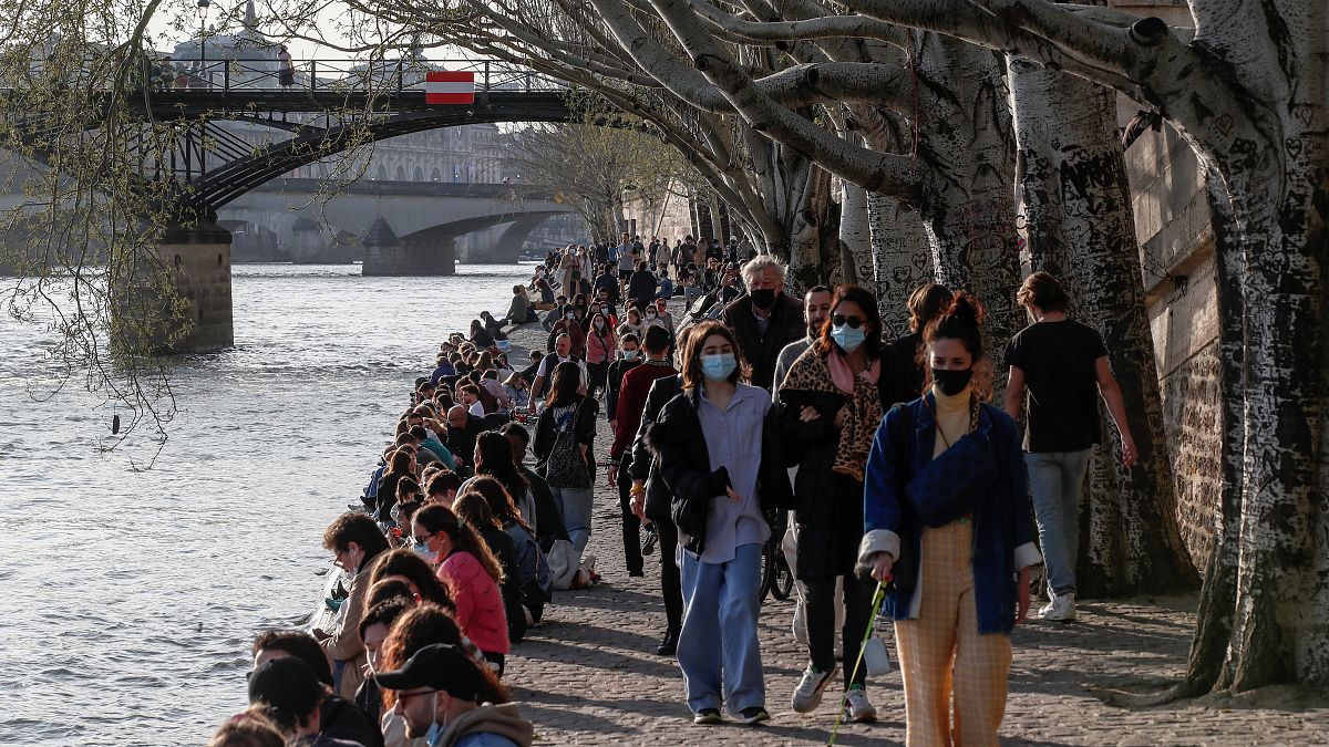 People stroll along the Seine river bank in Paris, where hospitals are under significant pressure from COVID-19 patients