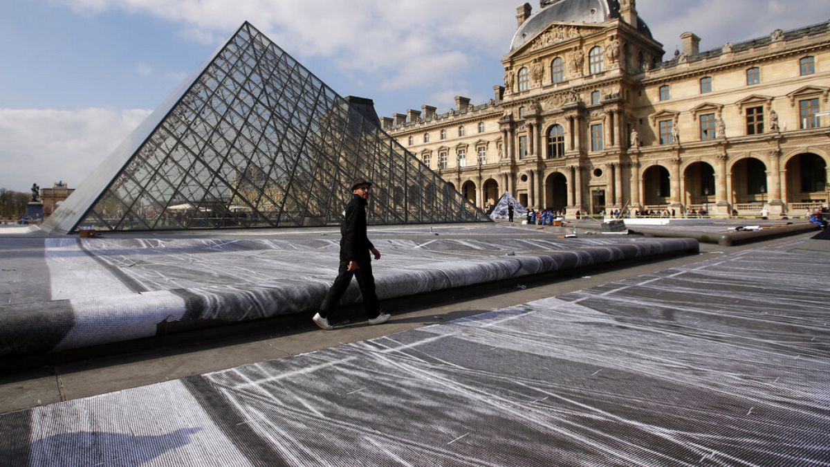 FILE: French street artist JR walks in the courtyard of the Louvre Museum near the glass pyramid designed by architect Leoh Ming Pei, in Paris, 27th March 2019
