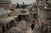  نساء يسرن في حي تضرر بشدة من الغارات الجوية في إدلب ، سوريا/ 12 مارس / آذار 2020 