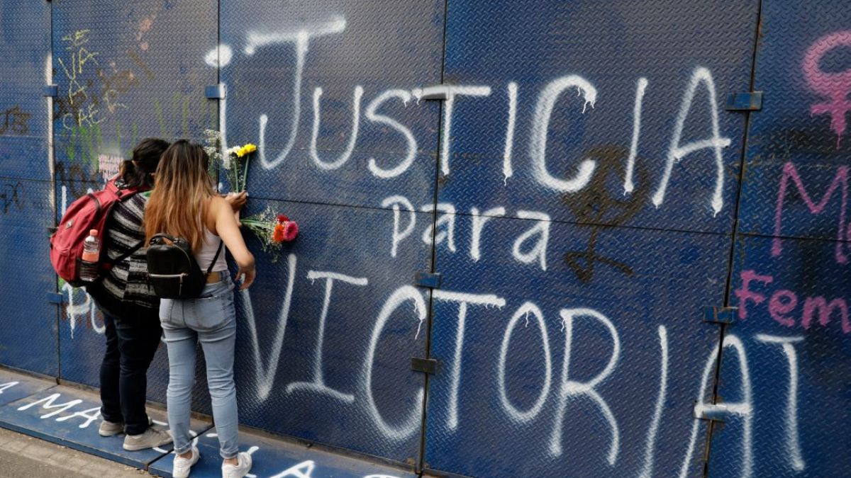 Jóvenes mexicanas colocan flores ante un grafiti que pide 'Justicia para Victoria' en Quintana Roo, México