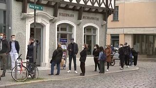 Menschen warten vor einem Geschäft in Weimar