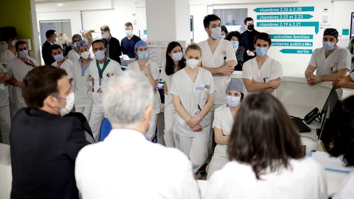 French President Emmanuel Macron speaks with staff in hospital